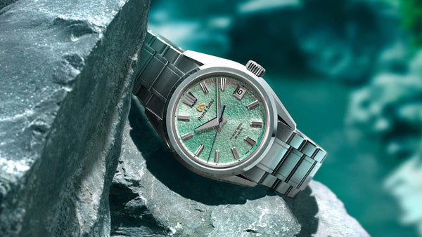 Grand Seiko Heritage Collection with textured green dial and stainless steel bracelet, resting on stone